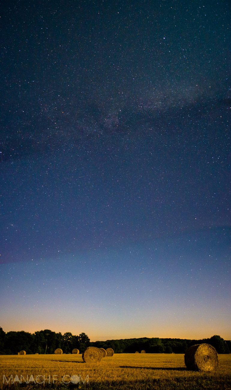 Panoramique d'un champ éclairé par la lune avec La voie lactée.